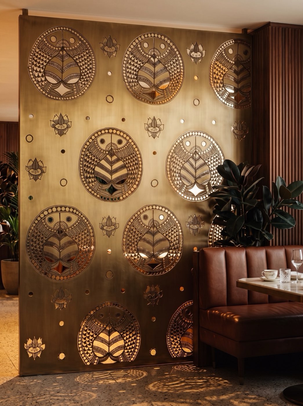 Waterjet laser-cut brushed antique brass screen partition in an upscale dining room.